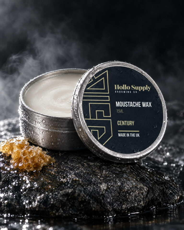 Moustache Wax (Century) by Hollo Supply Grooming Co., photographed on wet charcoal stone with water